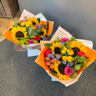 Sunshine & Smiles - Brighten someone's day with this cheerful arrangement bursting with sunshine yellow, vibrant pink and playful touches of purple. Beautifully presented in a colourful gift bag, this uplifting design is perfect for birthdays, congratulations, get well wishes or sending a little happiness just because.