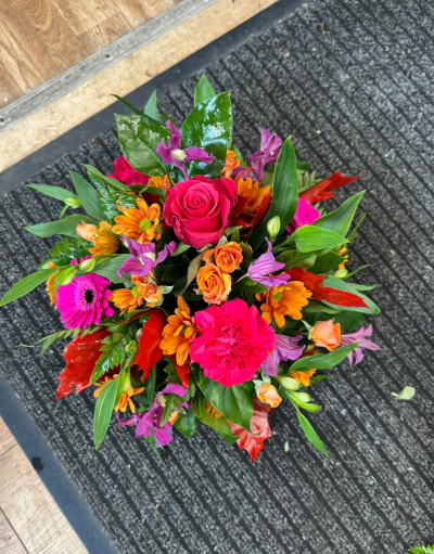 Autumn Reflections - A vibrant funeral tribute featuring rich autumnal shades of orange, cerise pink and purple, beautifully complemented by seasonal foliage. Thoughtfully arranged to create a colourful and uplifting display, this striking design offers a heartfelt way to celebrate treasured memories and honour the life of someone special.