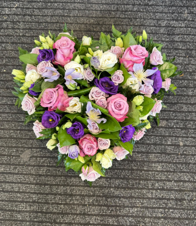 Everlasting Affection - A stunning heart-shaped funeral tribute featuring a romantic combination of soft pink, ivory, lilac and rich purple tones, beautifully complemented by lush greenery. Lovingly arranged to create a full, elegant display, this touching design symbolises everlasting love and cherished memories.