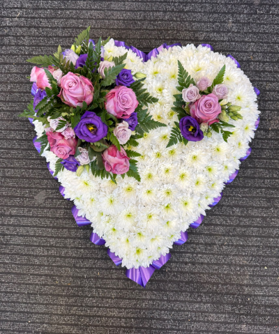 Precious Memories Heart - A beautiful, traditional heart-shaped funeral tribute featuring a soft white base, complemented by delicate pink, lilac and deep purple tones. Finished with elegant purple ribbon edging, this touching arrangement is a meaningful expression of everlasting love, offering a gentle and heartfelt way to remember someone dearly missed.